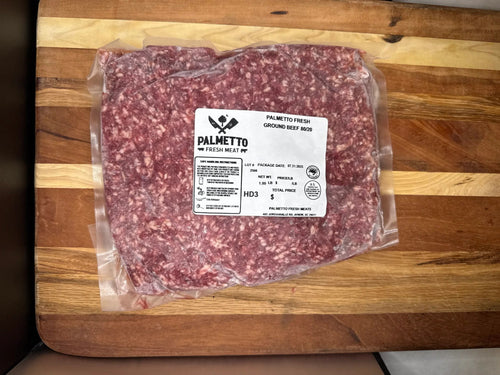 Packaged ground meat with a label on a wooden cutting board